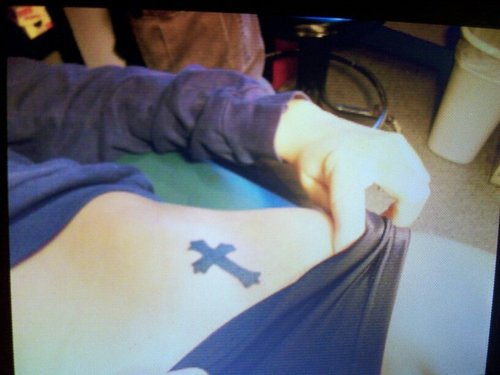 Girly small black cross tattoo on hip