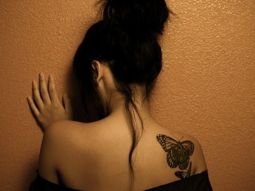 Red butterfly tattoo on the left shoulder blade