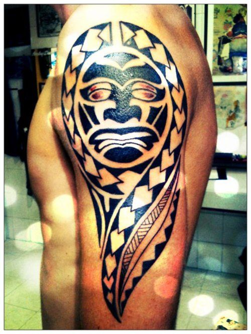 Shoulder maori tattoo with face on man's arm