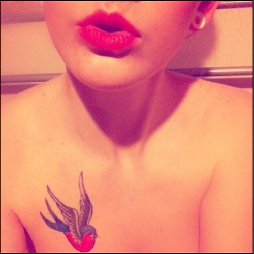 Red and blue swallow tattoo on girl’s chest