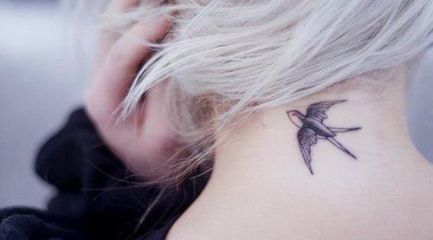 Simple black swallow tattoo on back of girls neck