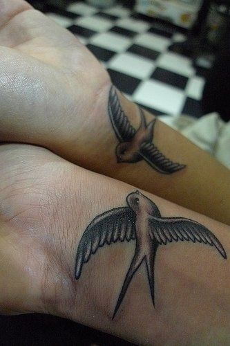 Two black swallow tattoos on bottom of wrists