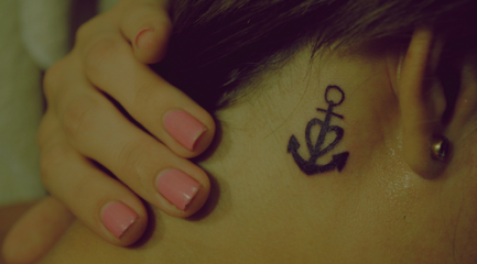 Black anchor tattoo with heart behind girls ear