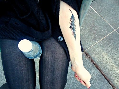 Black feather tattoo on girls forearm