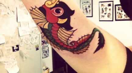 Colorful dragon fish tattoo on girls arm