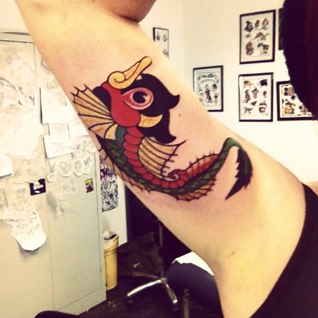Colorful dragon fish tattoo on girls arm