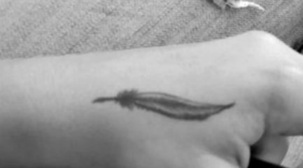 Tiny black hand feather tattoo