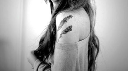 Two feathers tattoo on girls shoulder