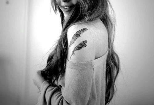 Two feathers tattoo on girls shoulder