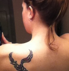 Black tribal phoenix tattoo on back of girls shoulder