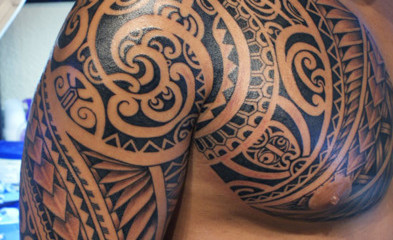 Swirly Polynesian chest and half sleeve tattoo